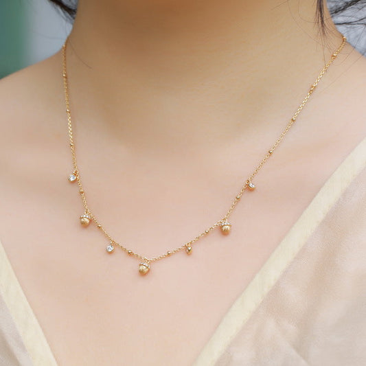 Gold necklace worn by a person with a blurred background