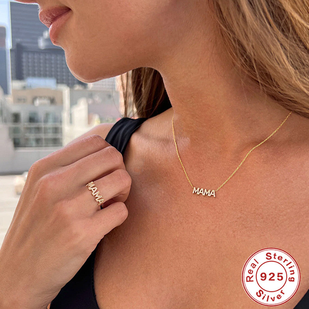 Woman wearing a 'MAMA' necklace and ring with a cityscape background