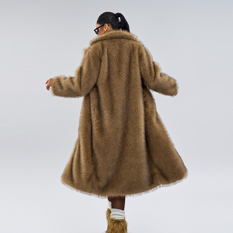 Person wearing a long brown fur coat on a plain background