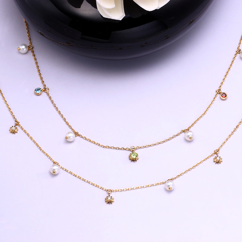 Gold necklace with pearls and small gemstones on a white background