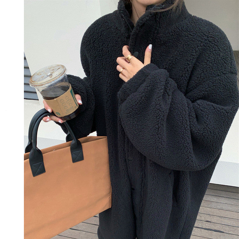 Person wearing a black coat holding a brown tote bag and a coffee cup.
