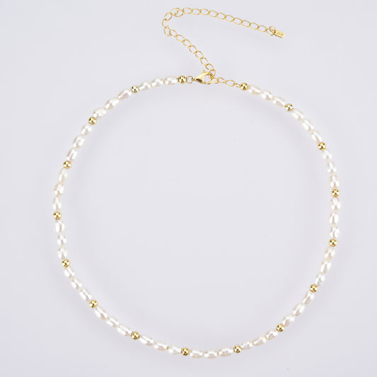 Necklace with alternating pearls and gold beads on a light gray background