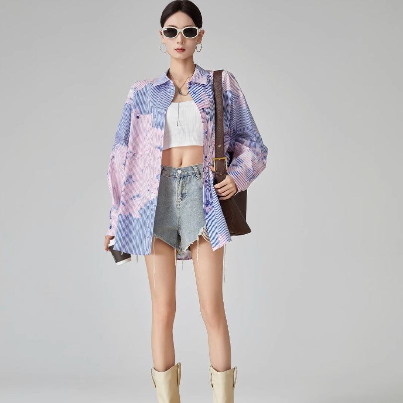 Woman wearing a colorful kimono-style jacket with denim shorts and yellow boots on a gray background