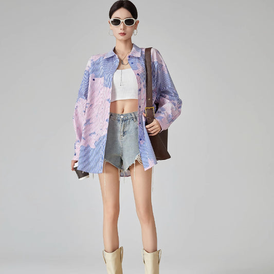 Woman wearing a colorful kimono-style jacket with denim shorts and yellow boots on a gray background