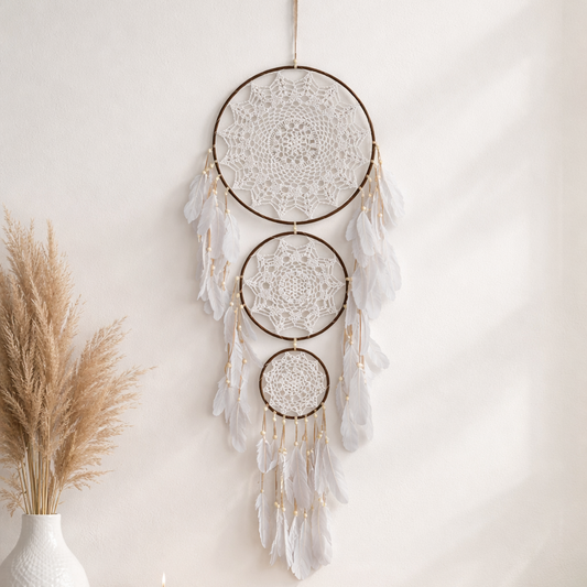 Decorative dreamcatcher hanging on a wall above a wooden surface with a candle and books.