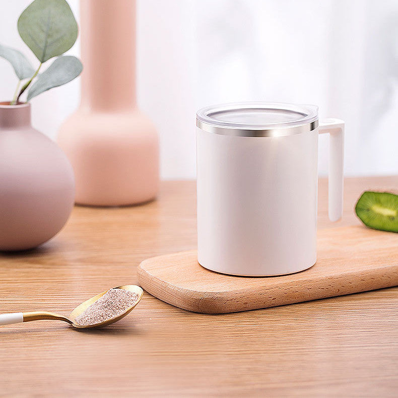 White mug with a lid on a wooden surface with decorative vases and a spoon.