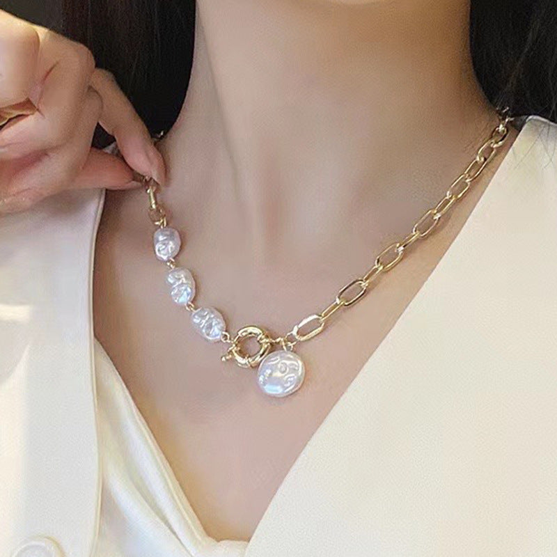 Gold chain necklace with pearl-like beads worn by a person