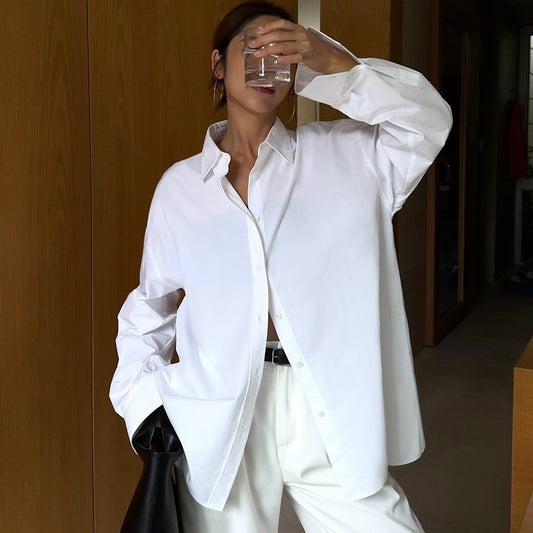 Person wearing a white shirt and pants, holding a glass of water indoors.
