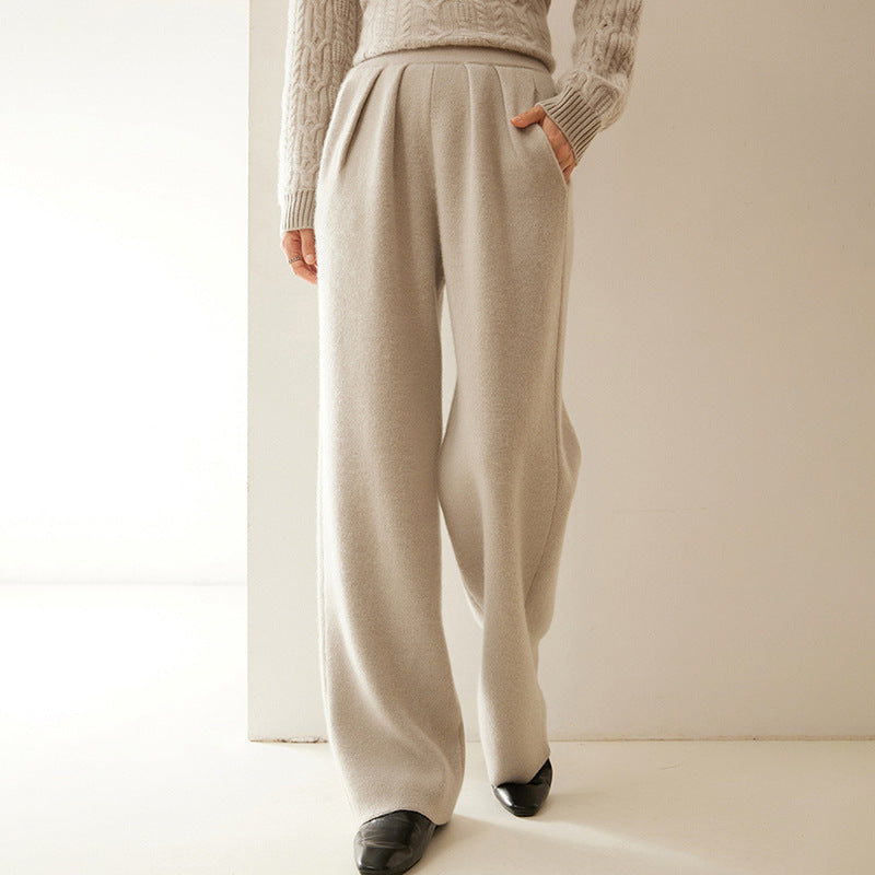 Person wearing beige knitted pants and sweater in a minimalistic setting