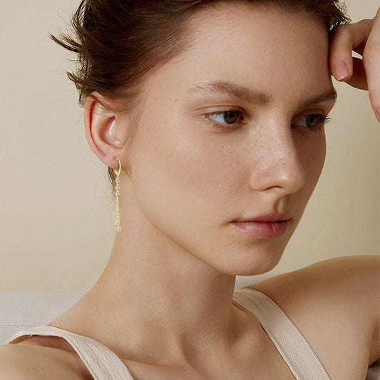 Close-up of a woman wearing gold earrings with a neutral background