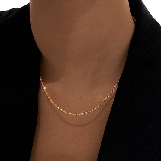 Gold necklace on a person wearing a black garment