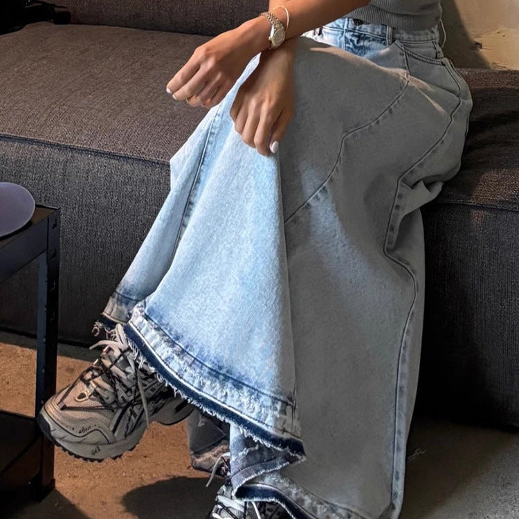 Person sitting on a couch wearing light blue jeans and gray sneakers.