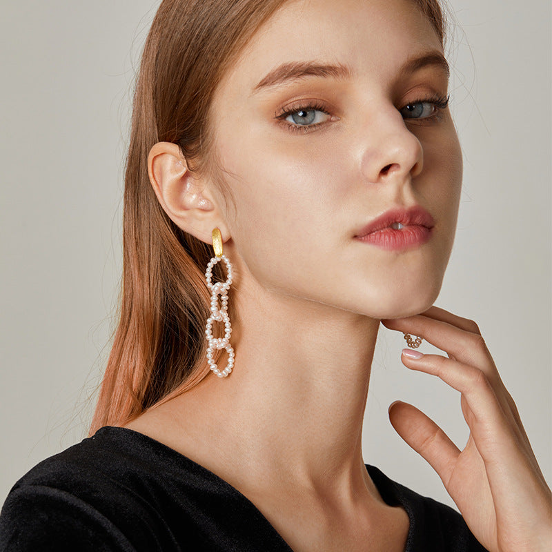 Woman wearing gold hoop earrings with a neutral background