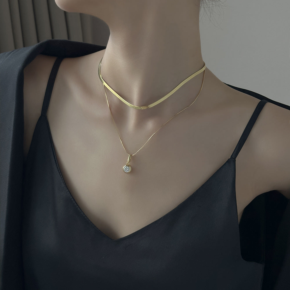 Mannequin wearing a gold necklace with a pendant against a neutral background