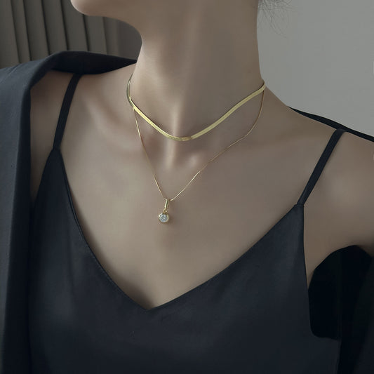 Mannequin wearing a gold necklace with a pendant against a neutral background