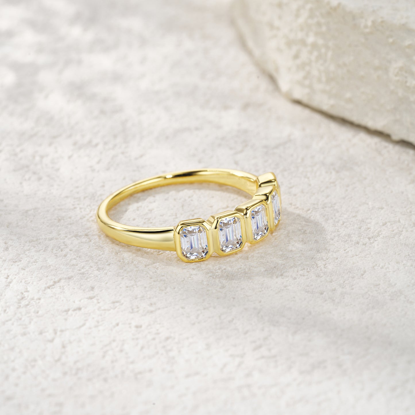 Gold ring with three clear gemstones on a light background