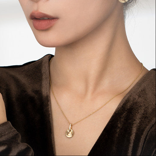 Woman wearing gold jewelry including earrings, necklace, and ring on a plain background