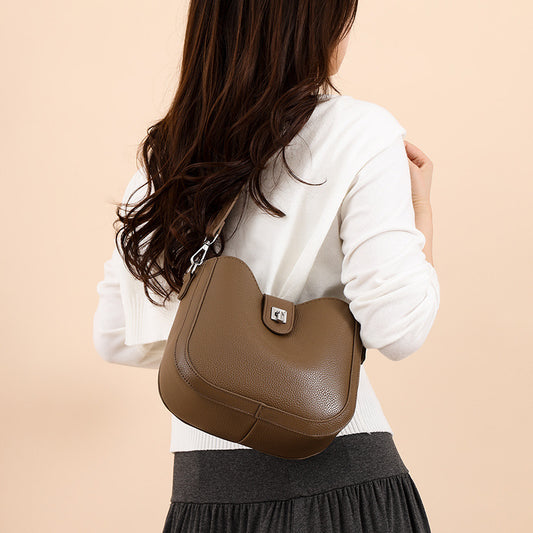 Woman holding a brown leather handbag against a beige background
