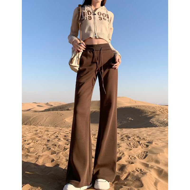 Person wearing a beige cropped hoodie and brown wide-leg pants standing in a desert landscape.