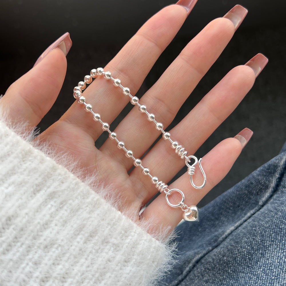 Silver beaded chain held by a hand against a dark background