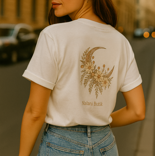 Person wearing a white t-shirt with a floral and moon design on the back, standing outdoors.