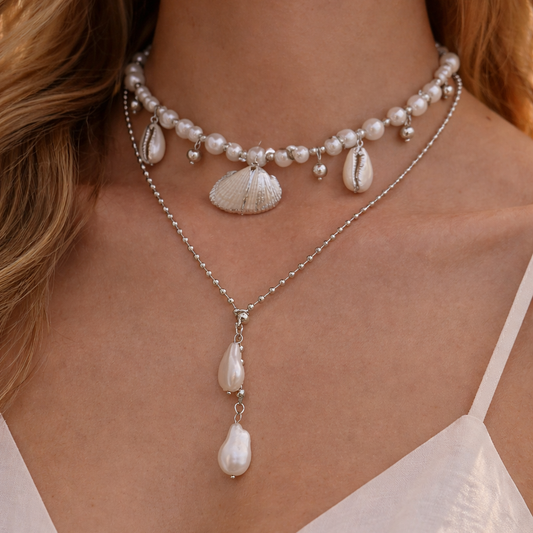 Close-up of a woman wearing a pearl necklace with seashell charms.
