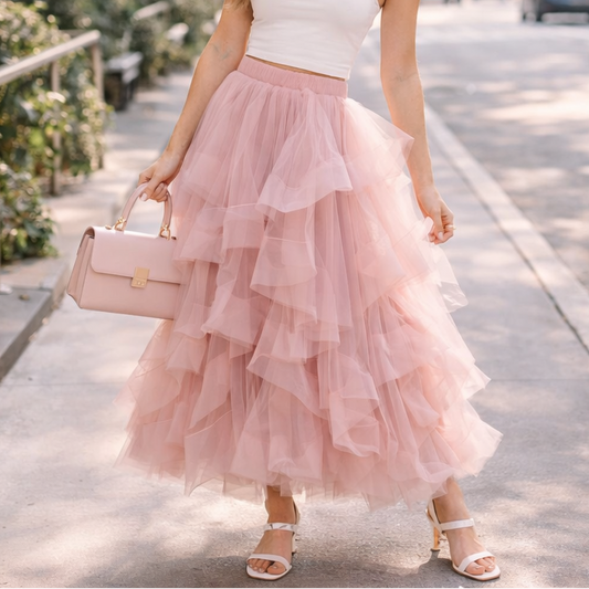 Woman in a white top and pink ruffled skirt walking on a city street.