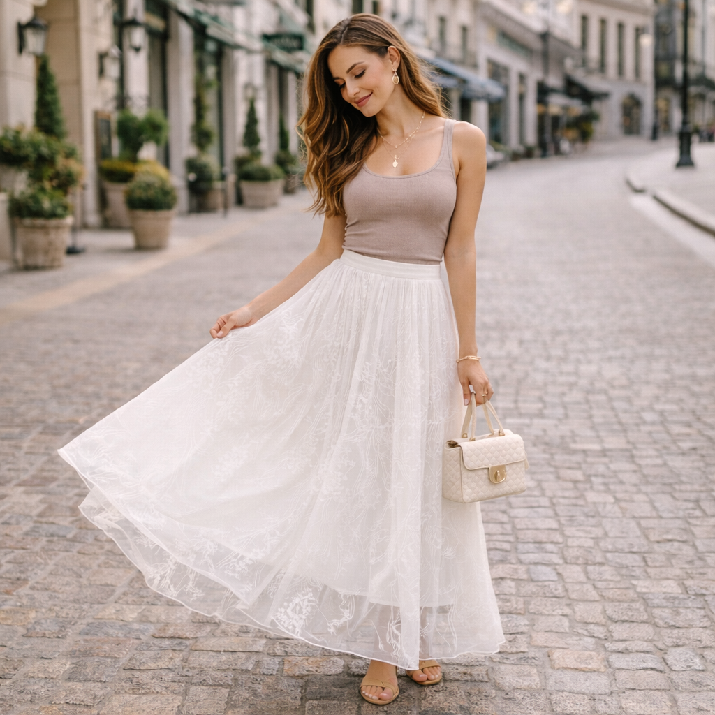 Woman in a beige top and white lace skirt walking on a street.