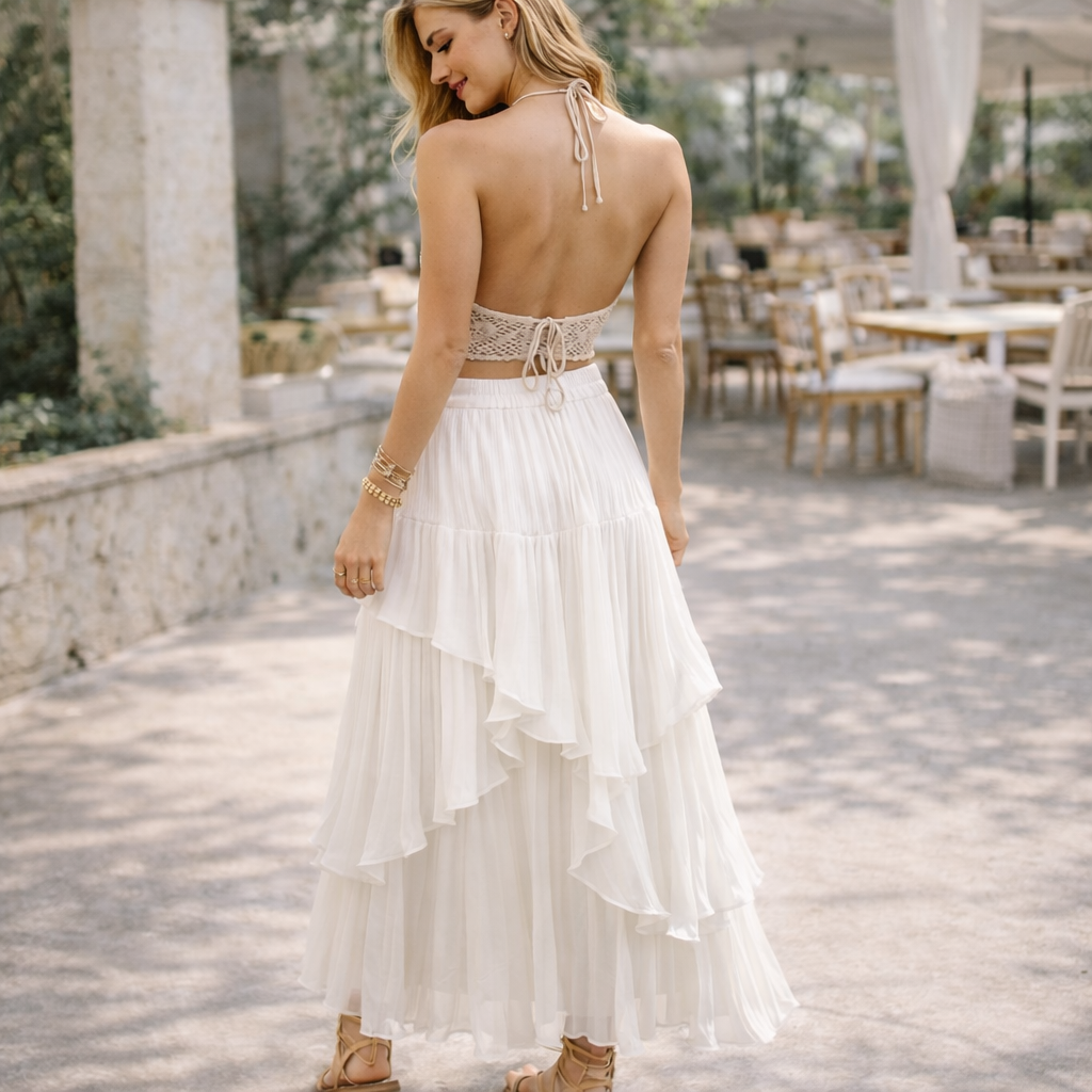 Woman in a white dress with an open back walking outdoors.